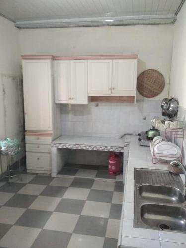 a kitchen with white cabinets and a checkered floor at Rumah Puan Homestay in Bandar Lampung