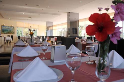 a table with a vase with red flowers on it at Falez Uygulama Oteli in Antalya