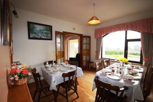 een eetkamer met een tafel met stoelen en een groot raam bij Pooreen House in Inverin