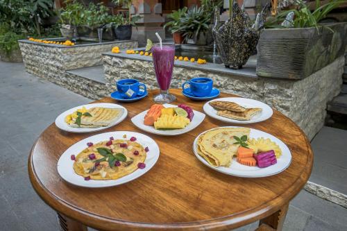 a wooden table with plates of food on it at Iman Homestay Ubud in Ubud