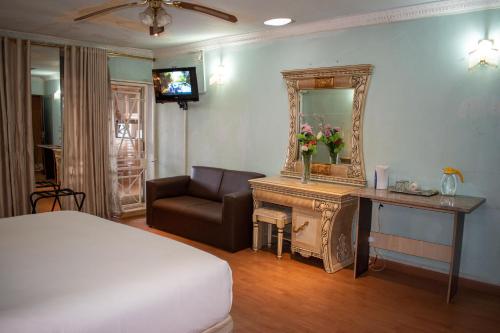 a bedroom with a bed and a mirror and a couch at Lenasia Guest Lodge in Lenasia