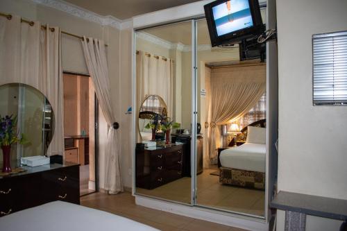 a bedroom with a bed and a mirror and a television at Lenasia Guest Lodge in Lenasia