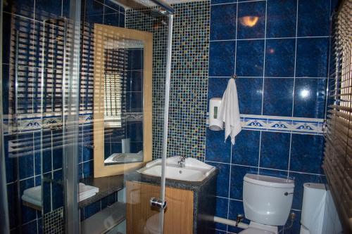 a blue tiled bathroom with a toilet and a sink at Lenasia Guest Lodge in Lenasia
