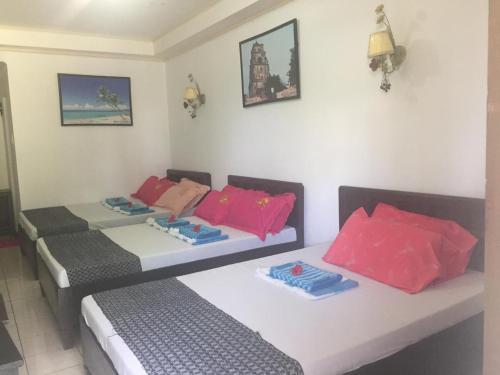 twee bedden in een kamer met roze en grijs bij RedDoorz Plus @ Rio Grande de Laoag Resort Hotel Ilocos Norte in Laoag