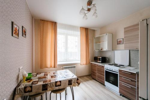 a kitchen with a table and a kitchen with a stove at Apartment on Bogomyagkova in Chita