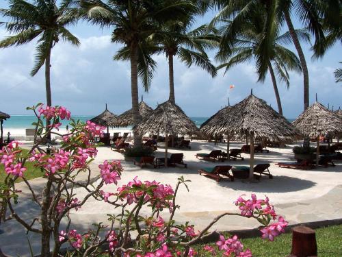 a beach with chairs and umbrellas and palm trees at Pinewood Beach Resort and Spa in Diani Beach