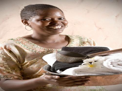 a woman holding a plate of towels and towels at Pinewood Beach Resort and Spa in Diani Beach