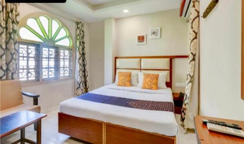 a bedroom with a bed and a desk and a window at SAROVAR INN in Chennai