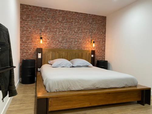 - une chambre avec un lit et un mur en briques dans l'établissement Cosy 2 Pièces Vue Mer Aux Parfums de Grasse, à Grasse