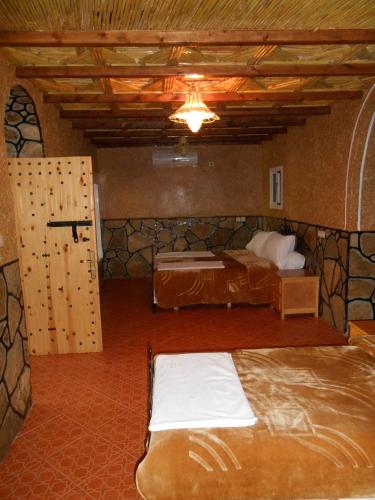 a bedroom with two beds and a door in a room at La Petite Gorge, Hôtel & Restaurant Todra Gorge in Tinerhir