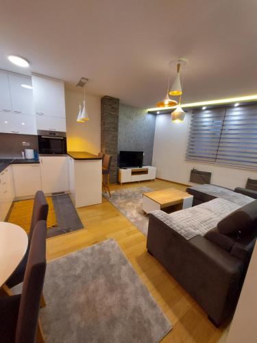 a living room with a couch and a table and a kitchen at Apartman Grey in Zlatibor