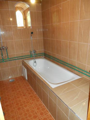 a bath tub in a tiled bathroom with a window at La Petite Gorge, Hôtel & Restaurant Todra Gorge in Tinerhir