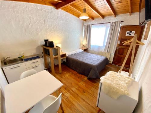 1 dormitorio con 1 cama, mesa y sillas en Apart Las Carretas en El Calafate