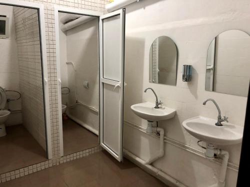 uma casa de banho com 2 lavatórios e um chuveiro com espelhos em Hotel El Maghreb Al Kabir em Nador
