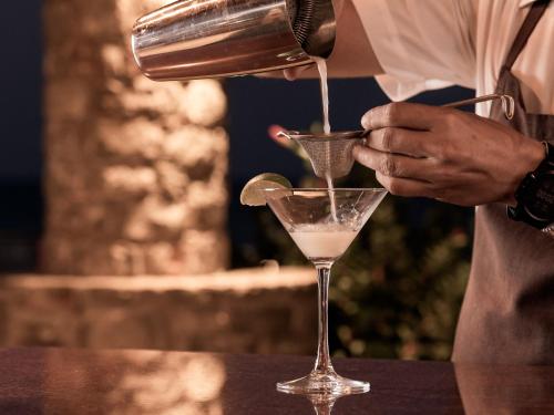 a person pouring a drink into a martini glass at Ikaros Beach, Luxury Resort & Spa - Adults Only in Malia