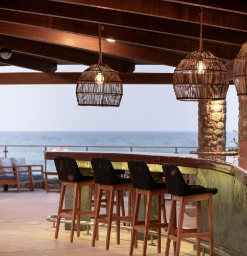 a bar with chairs and a table with a view of the ocean at Ikaros Beach, Luxury Resort & Spa - Adults Only in Malia