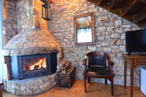 a stone fireplace with a chair and a mirror at Georgio's V Chalet Kalavrita in Kalavrita
