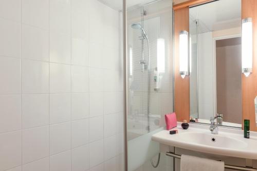 a white bathroom with a sink and a shower at ibis Marseille Provence Aéroport in Marignane