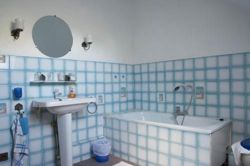 La salle de bains est pourvue de carrelage bleu, d'un lavabo et d'une baignoire. dans l'établissement Appartement en campagne a 1h30 de Paris, à Foucrainville