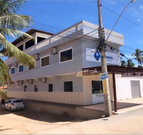 Un bâtiment blanc avec une voiture garée devant. dans l'établissement Pousada Praia Bela, à Maragogi
