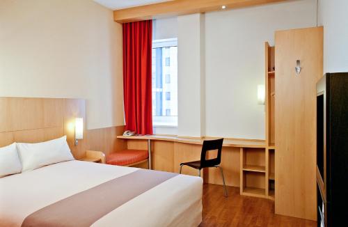 Schlafzimmer mit einem Bett, einem Schreibtisch und einem Fenster in der Unterkunft ibis Marseille Provence Aéroport in Marignane