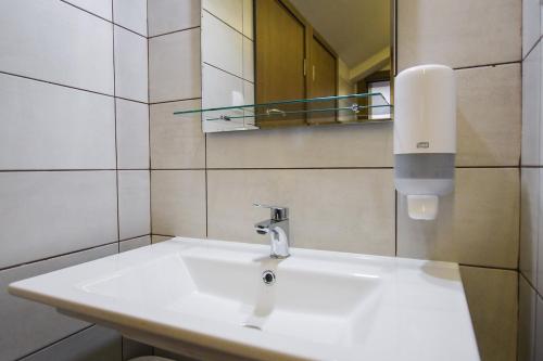 W łazience znajduje się biała umywalka i lustro. w obiekcie Hostel Atrijum w mieście Kladovo