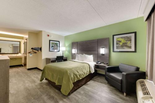 um quarto de hotel com uma cama e uma cadeira em Quality Inn Airport - Southeast em Birmingham