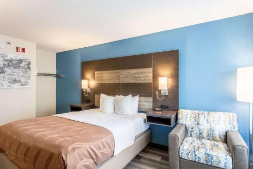 a hotel room with a bed and a chair at Quality Inn Branson On the Strip in Branson