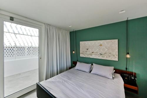 a bedroom with a green wall with a bed and a window at Casa Xonar in Silves