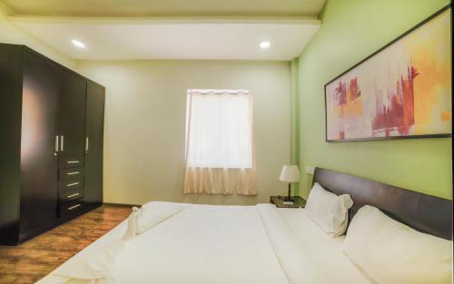 a bedroom with a large white bed and a window at Eternal Wave Apartments by Daystar Ventures in Calangute