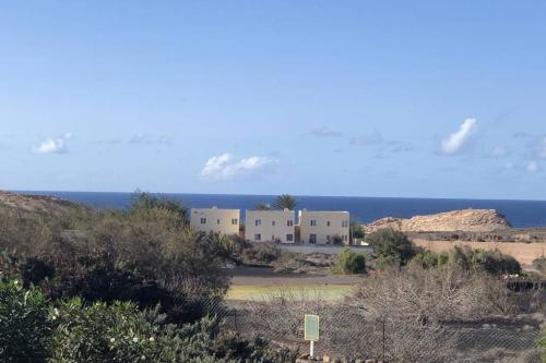 Apartamento en La Pared Fuerteventura vista mar في Pájara: مبنى في الصحراء مع المحيط في الخلفية