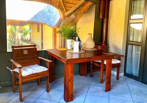 ein Holztisch und zwei Stühle sowie ein Tisch und Stühle sidx sidx sidx in der Unterkunft iKhaya LamaDube Game Lodge in Klipdrift