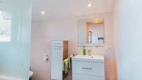 ein weißes Badezimmer mit einem Waschbecken und einem Spiegel in der Unterkunft Stubaier Bauern Appartement in Telfes im Stubai