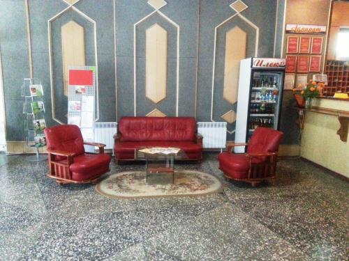 a waiting room with red chairs and a coffee table at Гостиница ИЛЕК in Aktobe