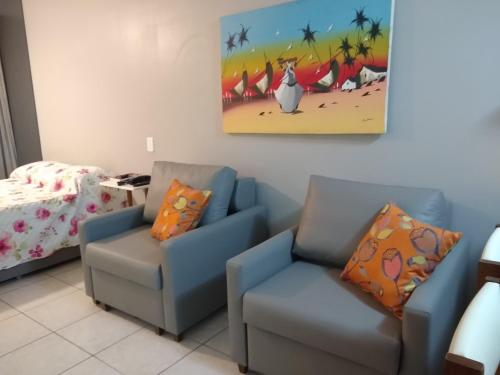 uma sala de estar com duas cadeiras e uma cama em Farol da Barra 209 em Salvador