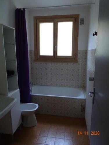 een badkamer met een bad, een toilet en een raam bij Pic de la Corne in Abondance
