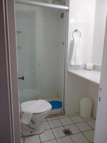 a white bathroom with a toilet and a shower at Farol da Barra 209 in Salvador