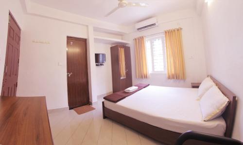 a bedroom with a bed with a desk and a window at Noah's Ark in Cochin
