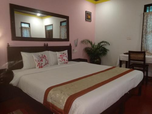 1 dormitorio con 1 cama grande y espejo en Marari Umapathi Beach Villa, en Mararikulam