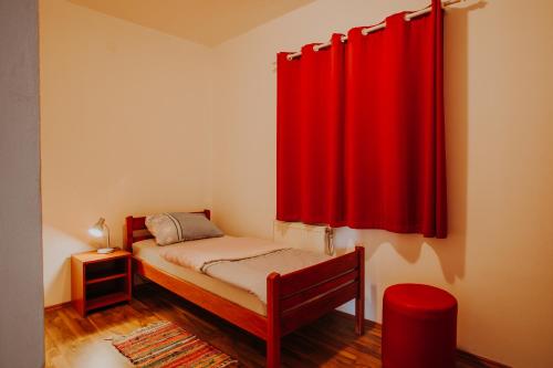 a bedroom with a bed with a red curtain at Sobe Anita in Vukovar