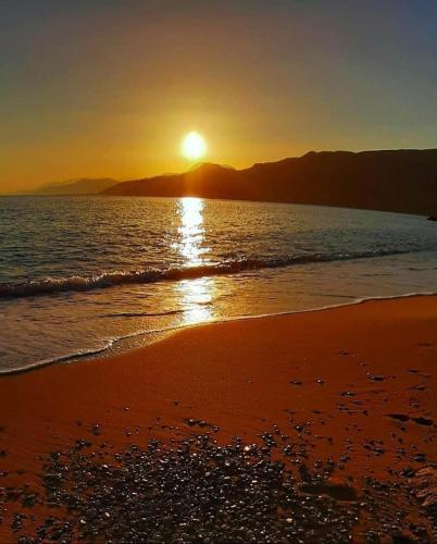 a sunset on a beach with the sun setting at Liviko View in Xerokampos