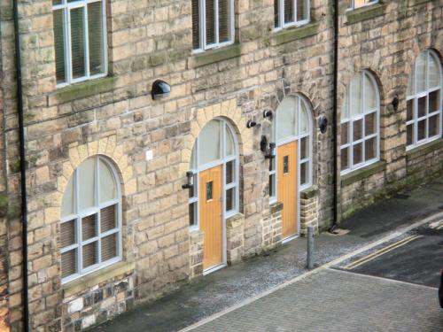 a brick building with orange doors on a street at Croft Mill in Hebden Bridge