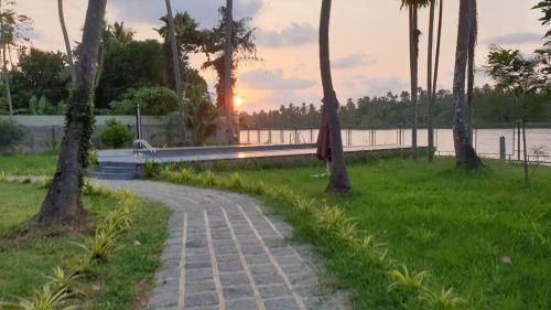a brick path in a park with a sunset in the background at Lhasa Ayurveda and Wellness Resort - A BluSalzz Collection, Kochi, Kerala in Cochin