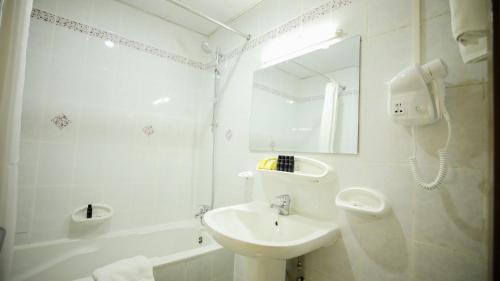 Green House Hotel Suites & Apartment في دبي: حمام أبيض مع حوض ومرآة