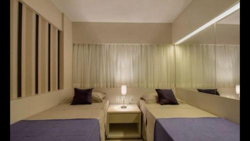 a bedroom with two beds and a mirror at Apto em Jatiúca, na Orla, Índia, JTR, LPires in Maceió