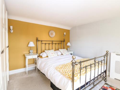 a bedroom with a bed and a yellow wall at Foundry Cottage in Norwich