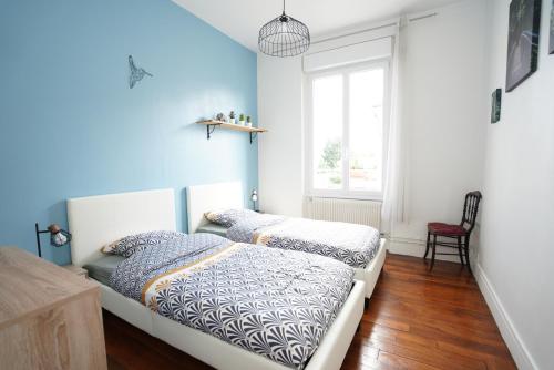 Cette chambre comprend 2 lits dans une chambre dotée de murs bleus et d'une fenêtre. dans l'établissement Grand appart à 2 pas des bords de Loire, à Orléans