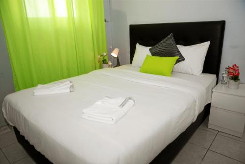 リスボンにあるホステル ドゥ カステロ リスボアの緑をアクセントにした白い大型ベッド付きのベッドルーム1室