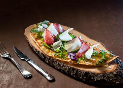 a pizza sitting on top of a wooden plate on a table at Panoramahotel Gürtl in Haus im Ennstal