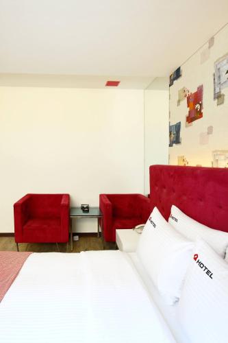 a bedroom with a bed and two red chairs at Q Hotel in Paju